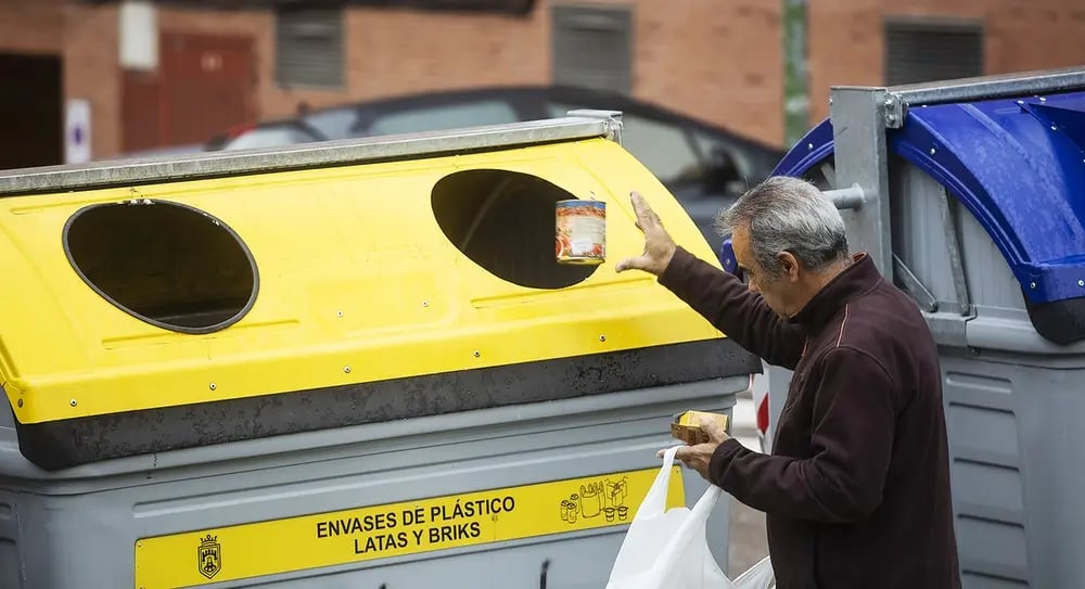 A person incorrectly disposing of steel food containers at the yellow bin, which is only reserved for beverage containers.