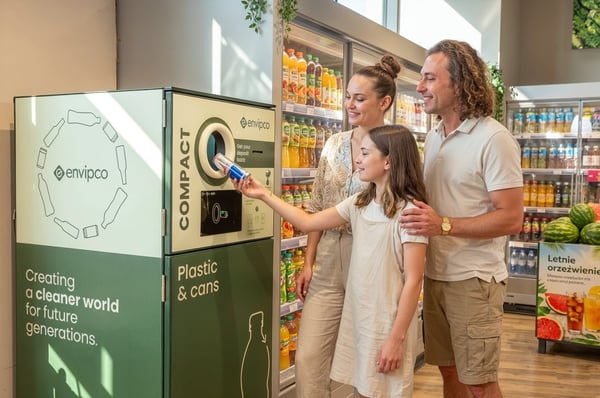 A family recyclign their empty beverage containers at an Envipco Compact reverse vending machine