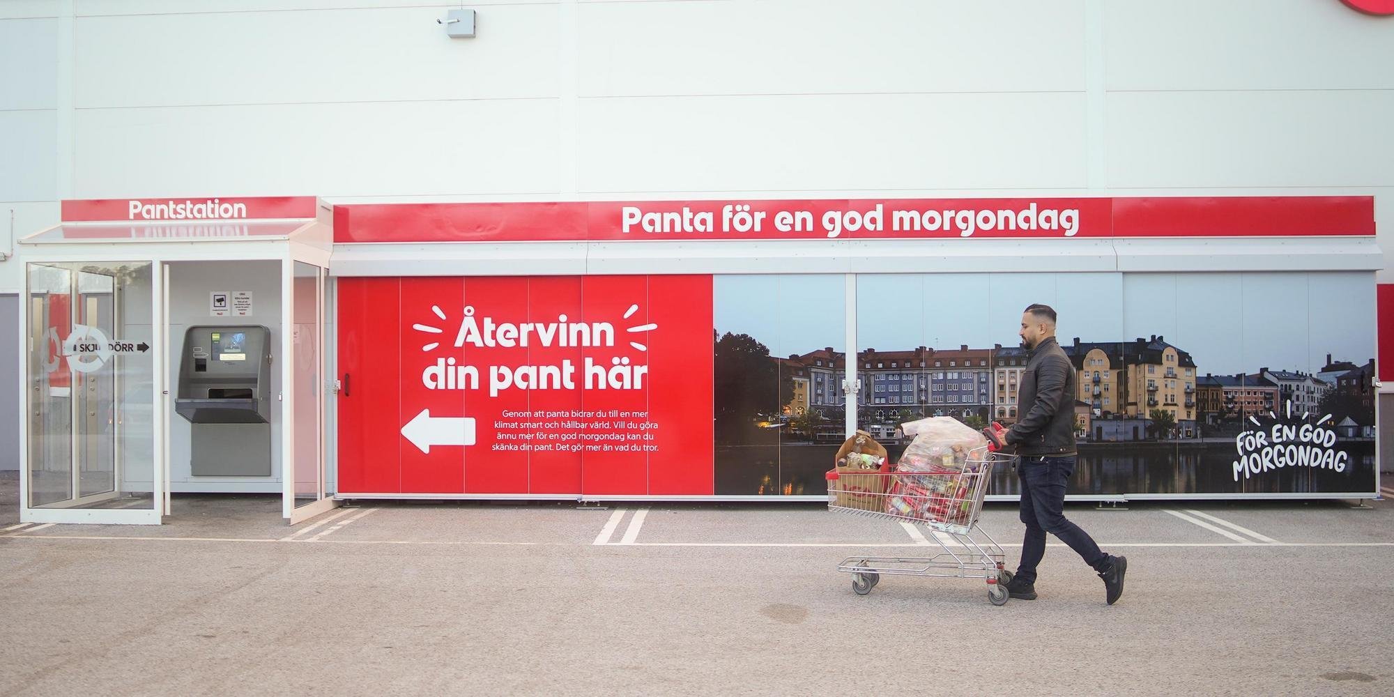 Cliente devolviendo una botella de plástico en una máquina de retorno de envases a la entrada de un supermercado