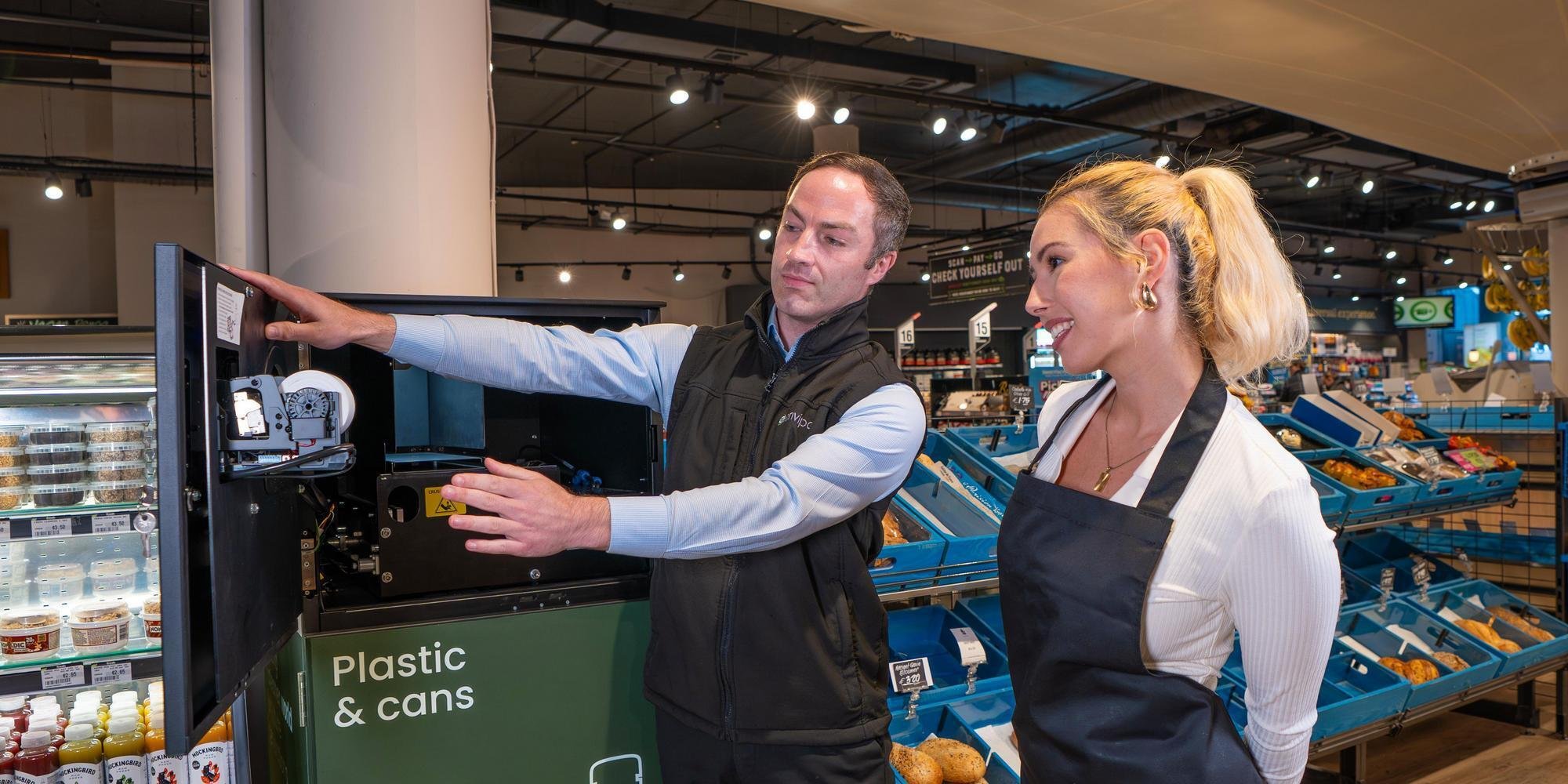 Empleado de tienda realizando el mantenimiento diario de una máquina de retorno de envases