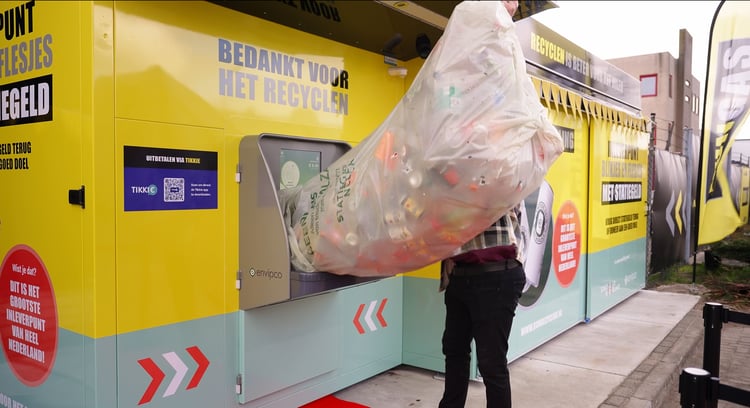 person recycling a massive bag of empty beverage containers with Envipco Quantum bulk reverse vending machine